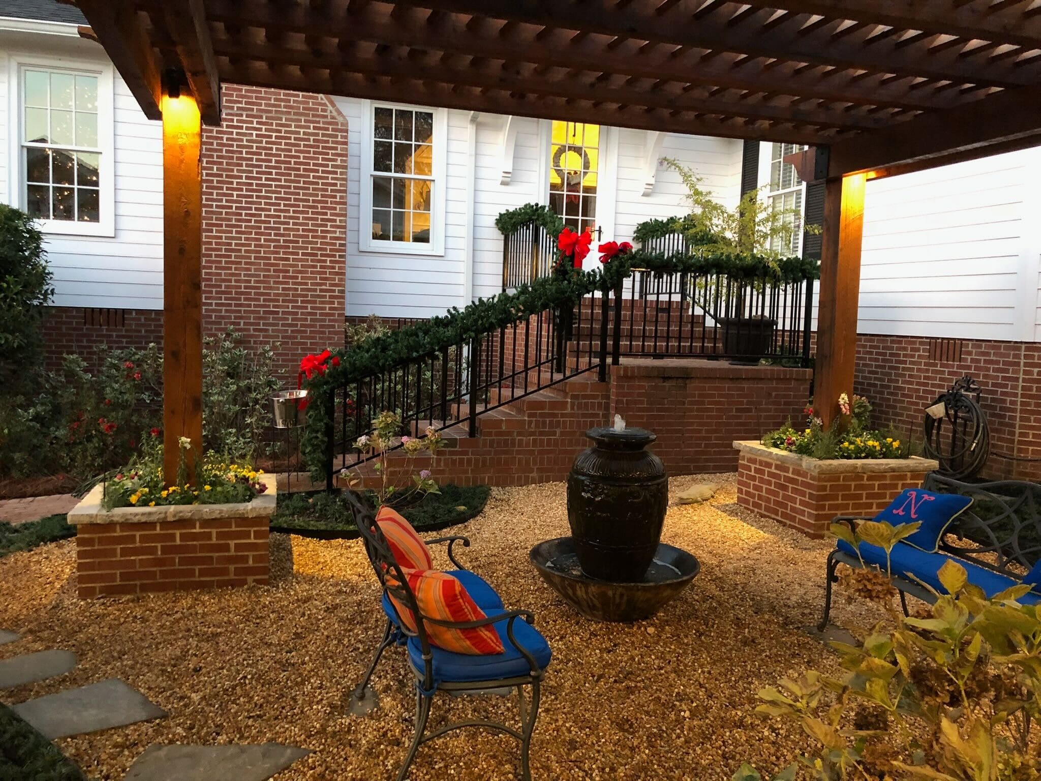 Custom outdoor living patio with pergola, seating area, and decorative landscaping at residential property