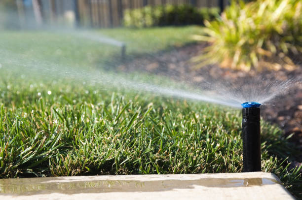 Technician checking irrigation controls in a Macon, GA landscape before testing sprinkler coverage
