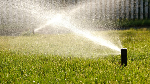 Technician testing irrigation zones beside a Warner Robins, GA lawn to improve sprinkler coverage